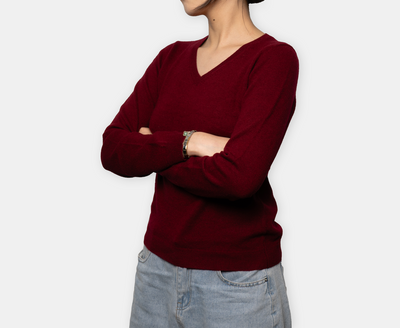 Women’s burgundy V-neck cashmere sweater with soft knit texture and tailored fit, offering warmth, elegance, and minimalist luxury design.