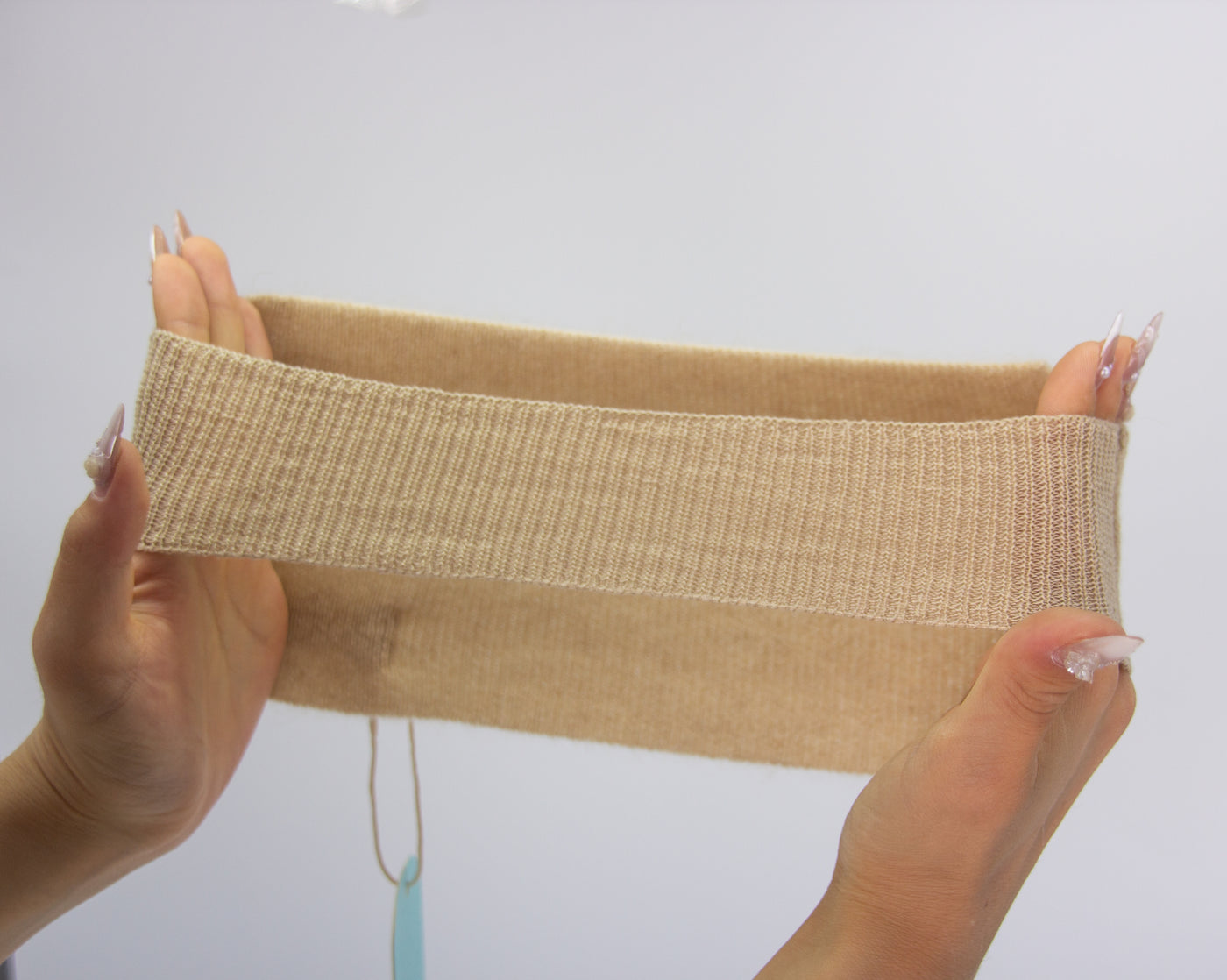 “Beige pure Mongolian cashmere baby bandage being gently stretched by hands, soft and breathable for newborn warmth and comfort”