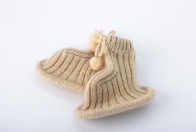 “Beige pure Mongolian cashmere baby booties with ribbed knit design and pom-pom ties, soft and breathable for newborn warmth”