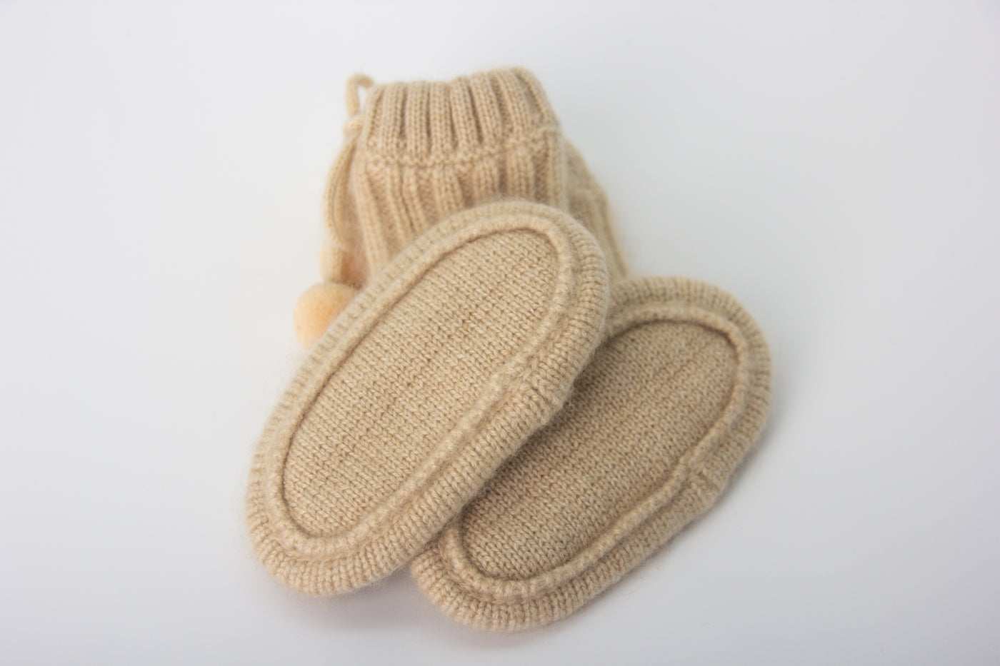 “Beige pure Mongolian cashmere baby booties with ribbed knit design and pom-pom ties, soft and breathable for newborn warmth”